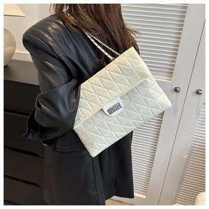 Close-up of diamond quilted stitching and silver metal turn-lock on a beige chain bag