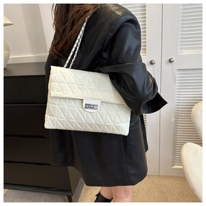 Close-up of white quilted chain bag featuring geometric triangle stitching and metal lock