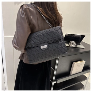 Detail view of a black quilted chain shoulder bag with a metallic turn-lock closure