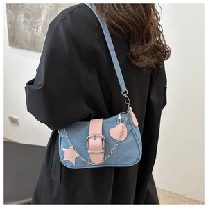 Dettaglio borsa a spalla in denim con ciondoli a cuore e stella rosa su modella
