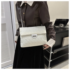 Detail shot of a large white quilted shoulder bag with silver chain strap on a model