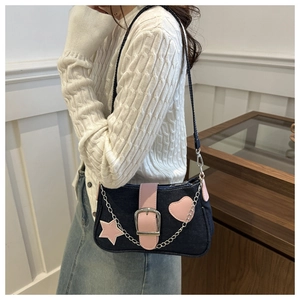 Dettaglio della borsa a spalla in denim con cuori in pelle rosa e catene argento
