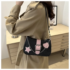 Dettaglio della borsa a stella in denim con cinturino in pelle rosa e catena indossata