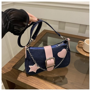 Dettaglio borsa a tracolla in denim blu con fibbia in pelle rosa e ciondolo a stella