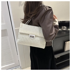 Detail of white quilted crossbody bag with silver clasp and chain strap on a model