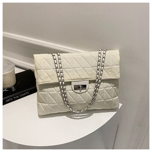 Detail of quilted beige shoulder bag with silver chain strap and metal turn-lock