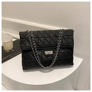 Detail of silver chain strap and rectangular twist lock on black quilted shoulder bag