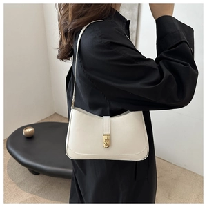 Detail of a minimalist white leather underarm bag featuring a gold rectangular twist lock