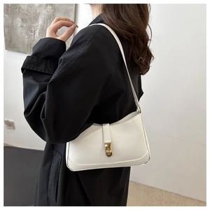 Detail of white PU leather baguette bag featuring a gold rotating metal lock closure