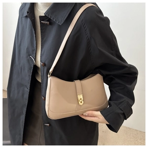 Close-up of minimalist tan leather underarm bag with vintage gold rectangular metal lock