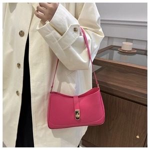 Detail view of pink leather underarm bag with gold buckle on a model in home setting