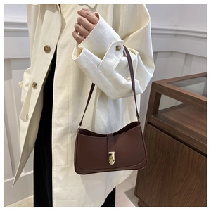 Detail of dark brown leather underarm bag with gold buckle on a stylish model