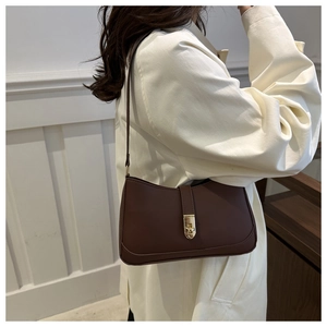 Detail of a dark brown underarm bag with a gold twist lock and matte leather finish