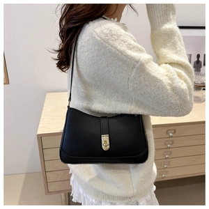 Detailed view of black crescent underarm bag with gold metal clasp on a model