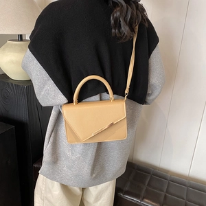 Women's brown pebbled leather crossbody flap bag with gold hardware shown on a model