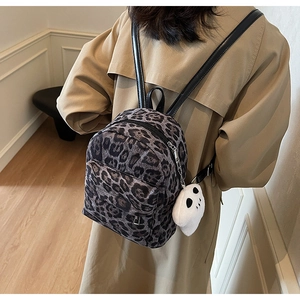 Detail of leopard print mini backpack with white ghost plush charm and thin leather straps