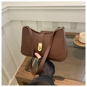 Detail of a dark brown crescent underarm bag featuring a vintage gold twist-lock closure
