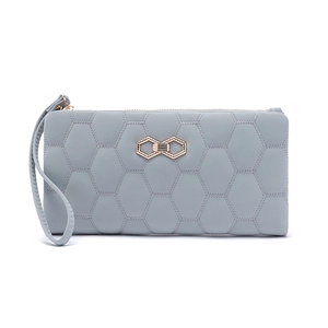 Close-up of light blue long wallet featuring hexagonal quilting and golden metal clasp