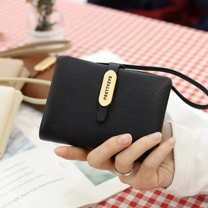 Close-up of black lychee texture wallet with a gold logo plate and wristlet strap