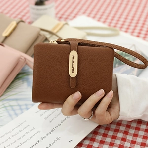 Close-up of brown litchi pattern leather wallet with gold metal buckle and wrist strap