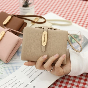 Close-up of pebble grain PU leather wallet with wristlet strap and gold metal emblem