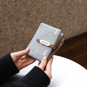 Detail of light blue PU leather wallet with cartoon mushroom pattern and golden brand plate