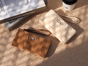 Detail view of quilted honeycomb texture and metal buckle on long zippered clutches