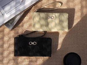 Detail of long quilted wallets with hexagonal patterns and metallic bow accents