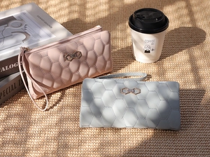 Detail of pink and gray quilted long wallets with hexagonal patterns and wristlet straps