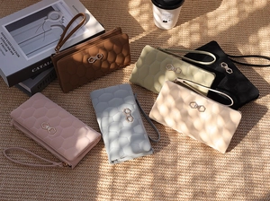 Quilted long wallets for women in multiple colors on a woven mat with natural sunlight shadow