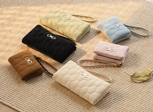 Detail view of honeycomb quilted faux leather wallets with elegant metal bow accents