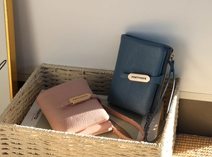 Detail of pink and blue pebble grain leather wallets with gold metal clasps and wristlets