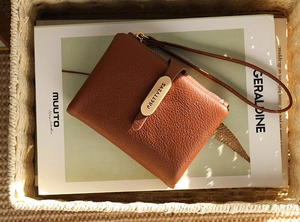 Detail of a brown lychee pattern leather wallet with wristlet strap and gold hardware