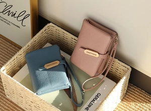 Close-up of litchi pattern PU leather wallets in blue and pink with metal brand plate