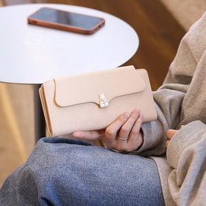 Detail of long cream PU leather wallet with quilted pattern and gold flower buckle