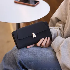 Detail of a black long wallet featuring a rose gold metal clasp and quilted texture