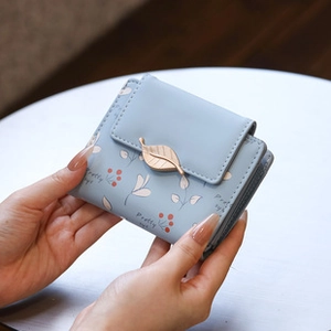 Close-up of light blue PU leather wallet with gold leaf clasp and plant prints