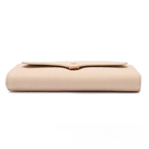 Detail of beige long wallet with quilted diamond stitching and golden metal buckle