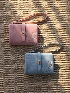 Close-up of pink and blue PU leather mini wallets with leaf embossing and wrist straps