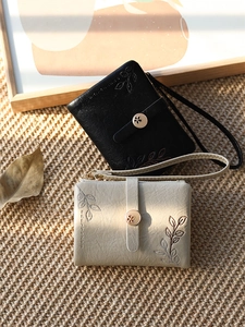 Close-up of floral embroidery and metal flower clasp on textured PU leather wristlet bags