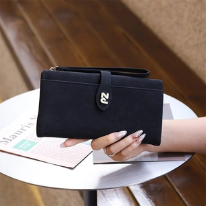 Detail of black matte long wallet with metal PZ logo and wristlet strap held in hand