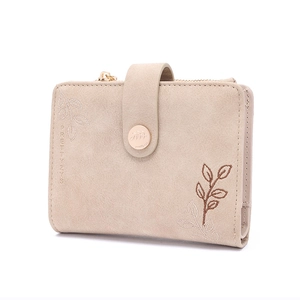 Close-up of beige wallet featuring elegant leaf embroidery and gold zipper detail