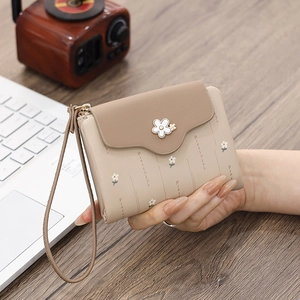 Close-up of a floral PU leather tri-fold wallet with wrist strap and enamel flower detail