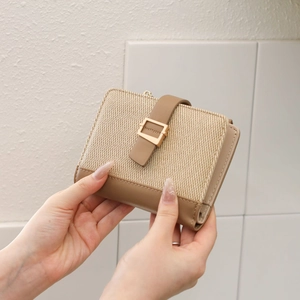 Detailopname van een beige geweven damesportemonnee van PU-leer met gouden gesp
