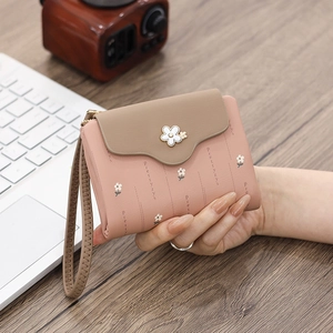 Pink trifold wallet detail showing floral print, wrist strap, and compact pocket design