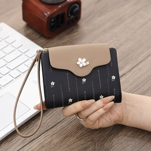 Close-up of a women's short PU leather wallet with floral buckle and logo print detail