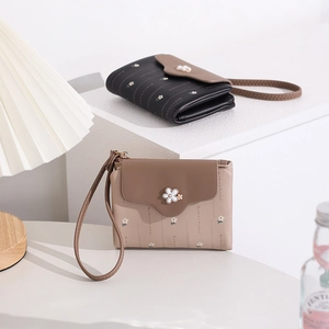 Detail view of black and beige PU leather wallets with wristlets and floral patterns