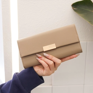 Detail der beigen Kunstlederstruktur mit Litschi-Maserung und goldener Schließe der Clutch