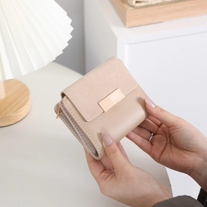 Detailed view of light pink compact wallet featuring a rose gold buckle and leather texture
