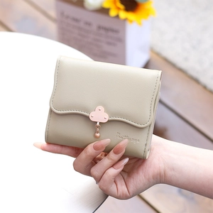 Close-up of a khaki tri-fold wallet featuring a cloud-shaped gold clasp and pendant